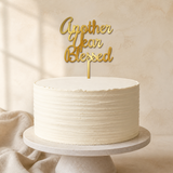Another Year Blessed Gold Mirror Acrylic cake topper displayed on a cake