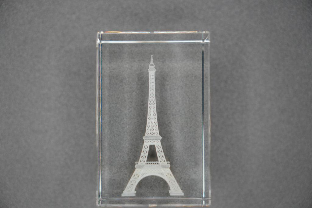 Clear glass block with Eiffel Tower engraving on a gray background