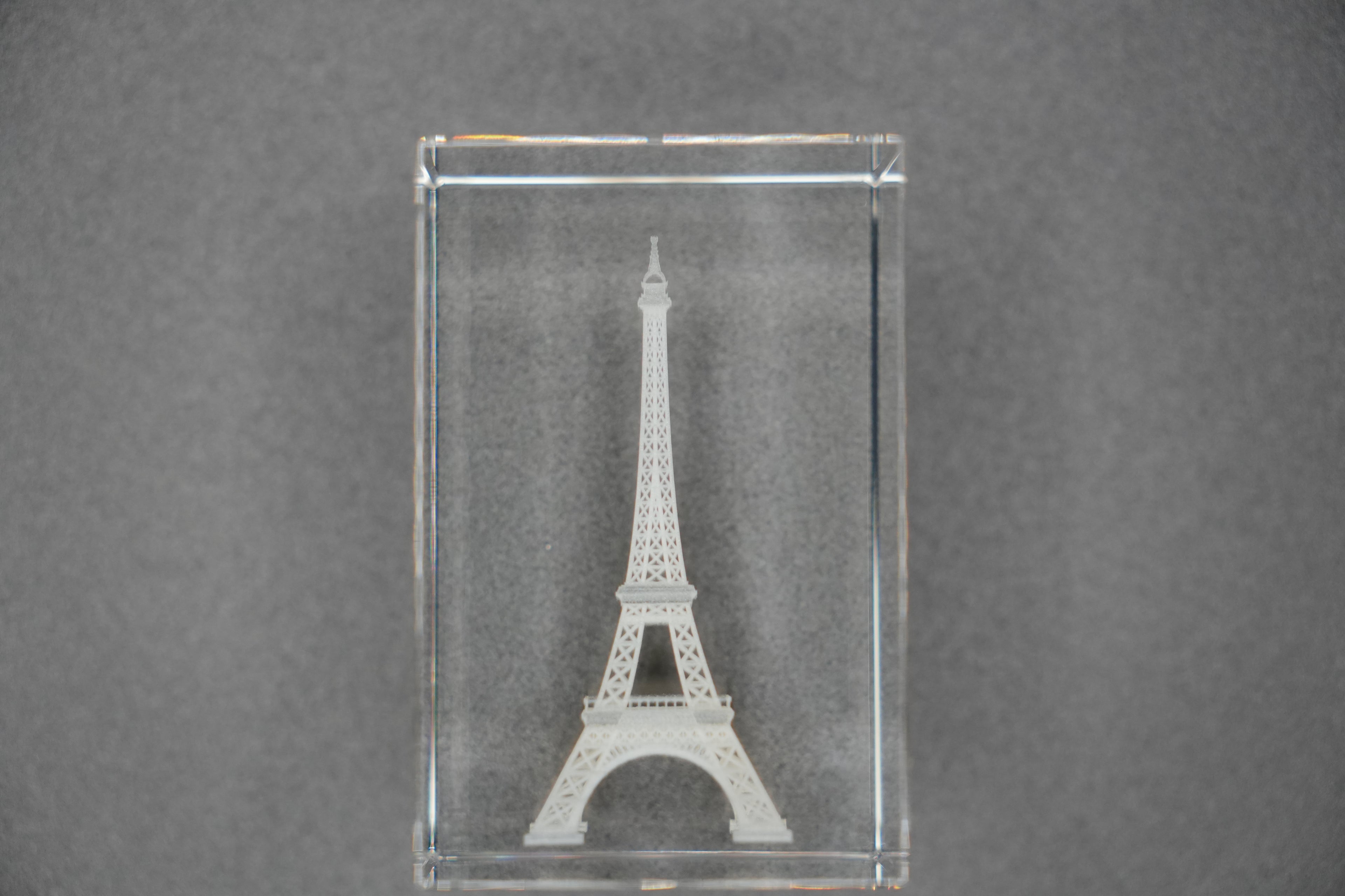 Clear glass block with Eiffel Tower engraving on a gray background